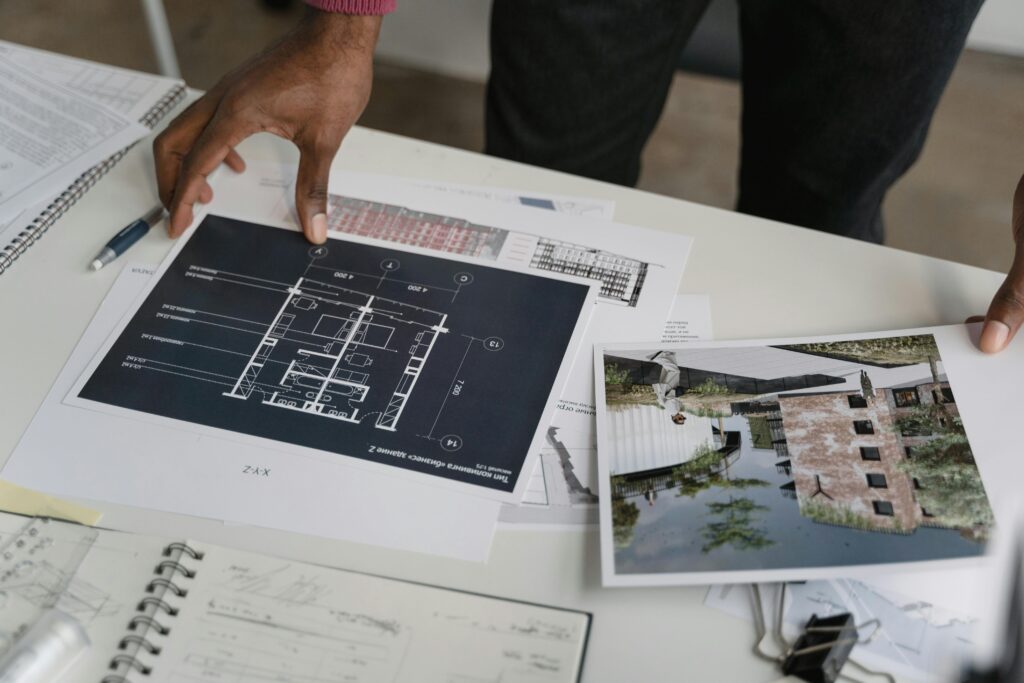 Architect hands reviewing architectural blueprints and design documents in an office setting.